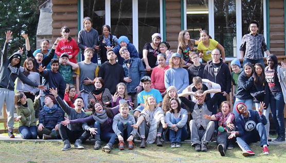 Large group photo of smiling youth waving